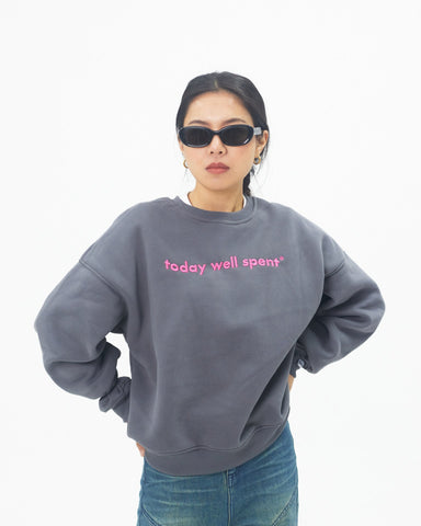 Person wearing a gray sweatshirt with 'today well spent' text and sunglasses on a white background